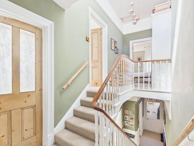 There is a spacious hallway with high ceilings, staircase with period detailing and split-level landing