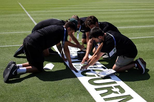 Ground staff paint the Eastbourne wording onto the grass of centre court during Day Two