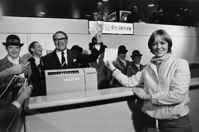 British airline entrepreneur Freddie Laker (1922 - 2006, centre, left) sells the first ticket for a flight on his Laker Airways Skytrain service to passenger Ann Campbell (right) at Gatwick Airport, Sussex, 26th September 1977.  (Photo by Frank Barratt/Evening Standard/Hulton Archive/Getty Images)