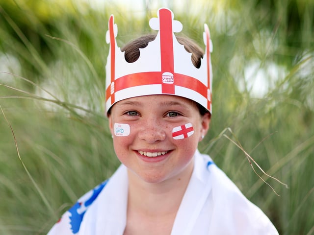An England fan wearing a hat poses for a photo outside the Brighton & Hove Community Stadium.