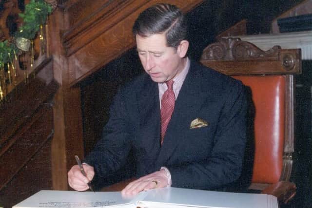 Charles signing the visitor book at Wilton Park