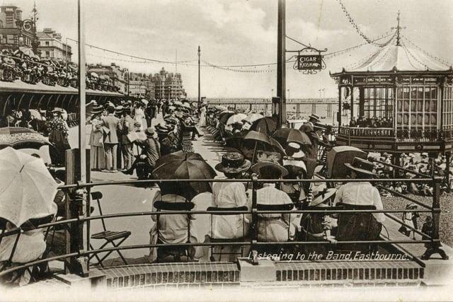 Residents listening to music on the seafront. A sign says 'cigar kiosk'