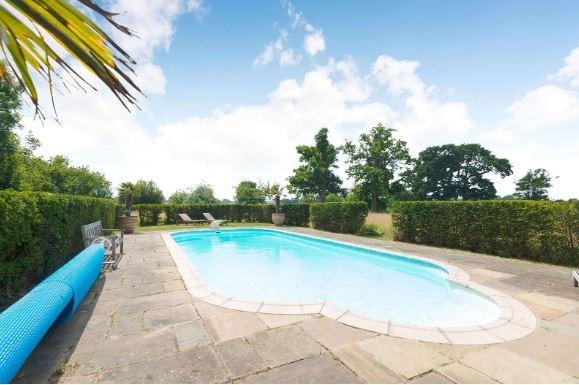 A pathway across the lawn leads to the outdoor swimming pool which has recently been re-designed and is enclosed by newly-installed fencing.