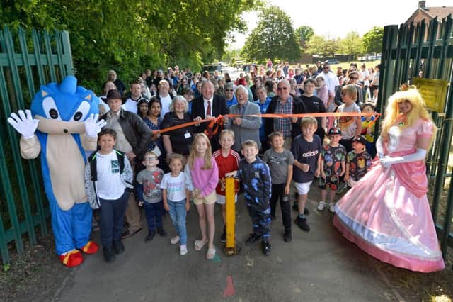 Councillor Chris Mullins (centre right) cutting the ribbon, with Crawley Borough Council leader Michael Jones and some of the families who were at the opening of the Mill Pond playground. 