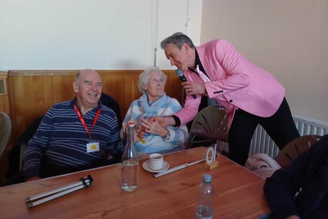 Performer Mark A Wright serenades two delighted blind veterans.