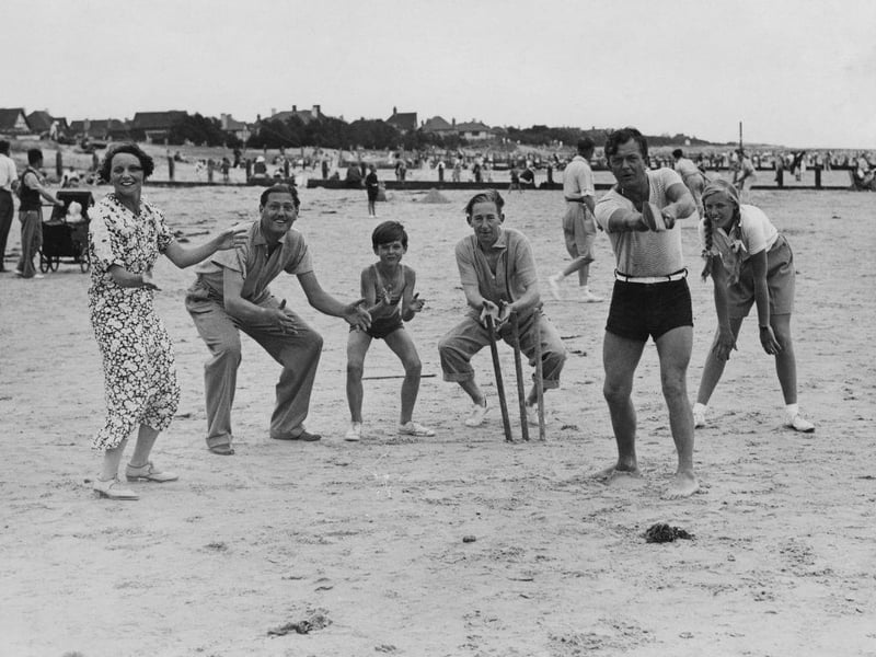 English comic actor Claude Hulbert (behind wicket) and entertainer Bobby Howes (batting) playing cricket on the beach during a family holiday in Felpham, West Sussex on 11th August 1934. On the right is Pamela Hulbert, daughter of Claude's brother Jack Hulbert and actress Cicely Courtneidge, who are also on the holiday. On the left is Claude's wife, actress Enid Trevor.