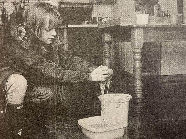A resident tries to soak up some of the water in her home.