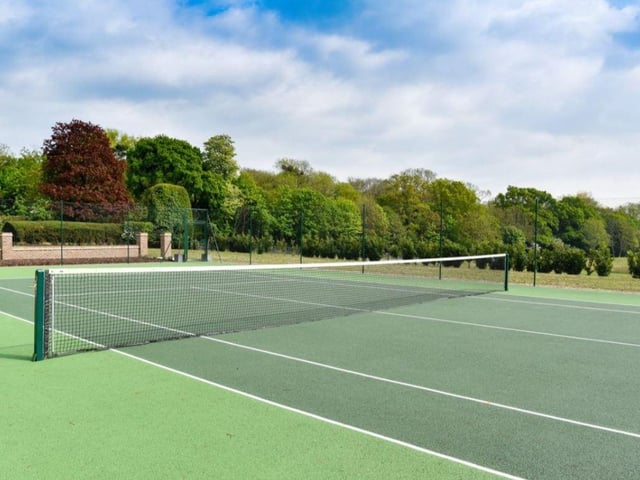 The tennis court is next to the outdoor swimming pool