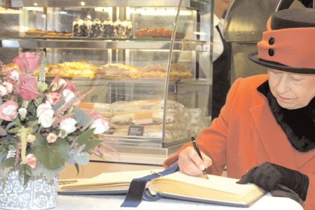 The Queen signs a guestbook during her visit to Crawley in 2006