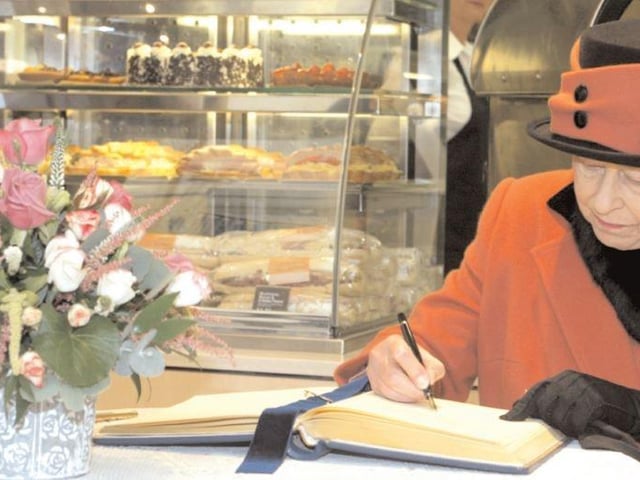 The Queen signs a guestbook during her visit to Crawley in 2006