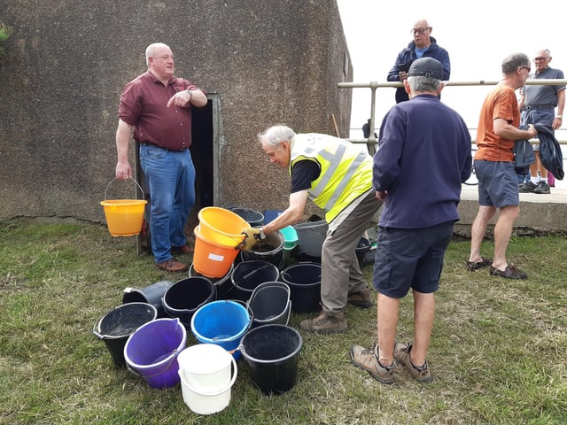 A bucket chain of volunteers from Ferring History Group and Ferring Conservation Group, including Worthing West MP Sir Peter Bottomley, form a bucket chain to bail out nine inches of water from the Ferring pillbox