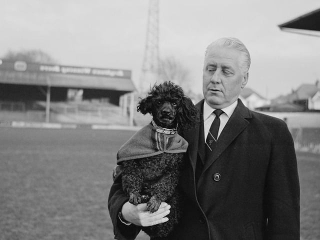 Former Scottish footballer and manager of Brighton & Hove Albion, Archie Macauley is pictured holding his pet poodle dog 'Scampi' on the pitch at the club's Goldstone Ground in Hove on 8th January 1966.