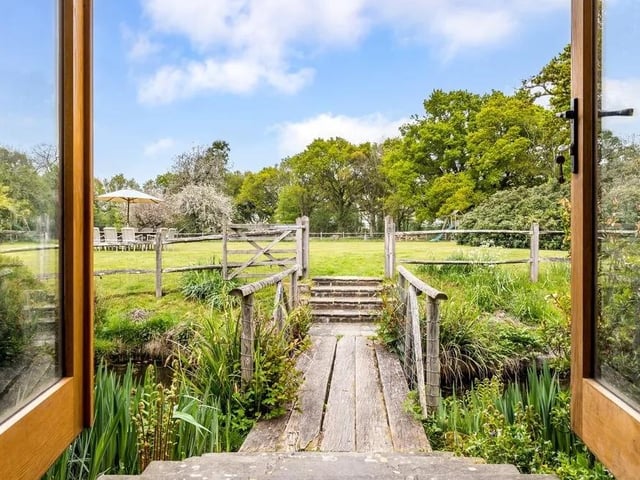 From the kitchen, French doors open to a wooden bridge over the pond.