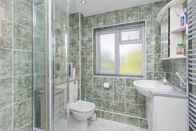 The family bathroom has an enclosed corner shower cubicle, a low level WC and a vanity unit