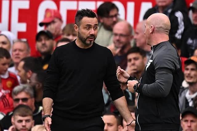 Brighton's Italian head coach Roberto De Zerbi (L) has a word with fourth official Simon Hooper (R) during the English Premier League football match between Manchester United
