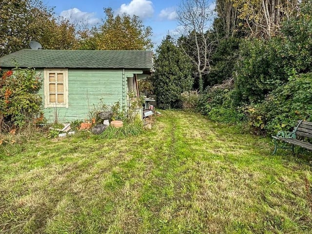 Steps lead to an expansive lawn, surrounded by mature shrubs and bushes