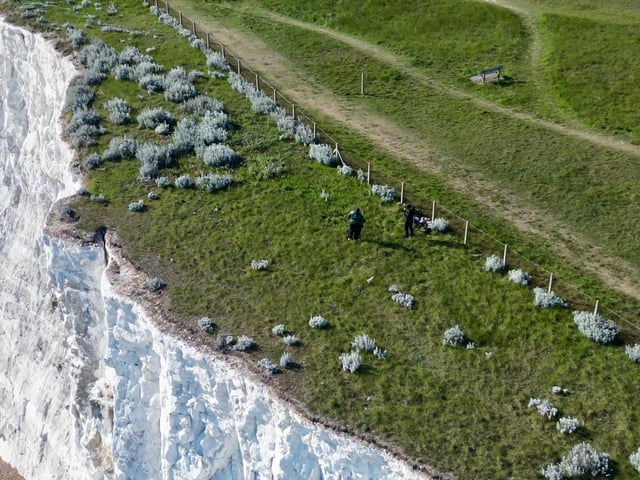 People climbing over the barrier near the cliff edge in Saltdean on Thursday, May 7. Photo: Eddie Mitchell