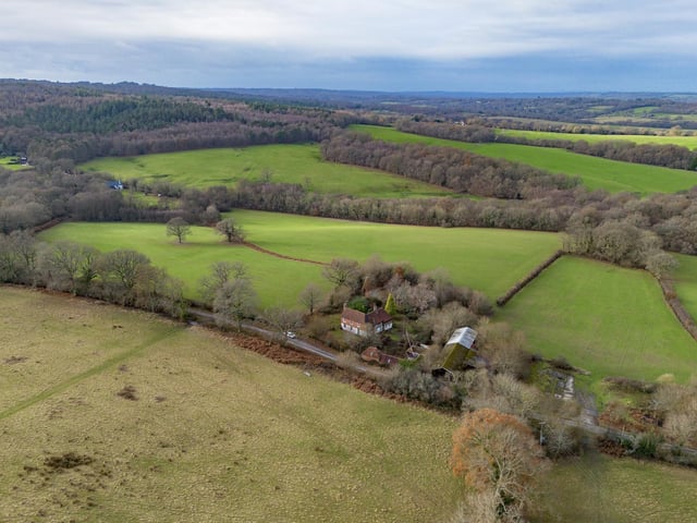 A farmhouse with farm buildings set within 119 acres on the edge of the Ashdown Forest is on the market