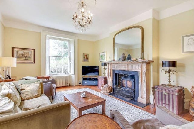 The drawing room has a dual-aspect and features an original open fireplace with an ornate carved timber surround and inset woodburner.