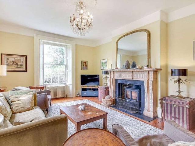 The drawing room has a dual-aspect and features an original open fireplace with an ornate carved timber surround and inset woodburner.