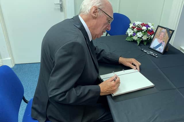 Cllr John Barrett signs a book of condolences to the Queen