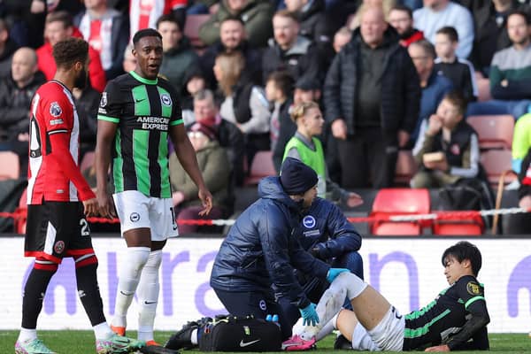 Kaoru Mitoma of Brighton & Hove Albion receives medical treatment after being fouled by Mason Holgate of Sheffield United