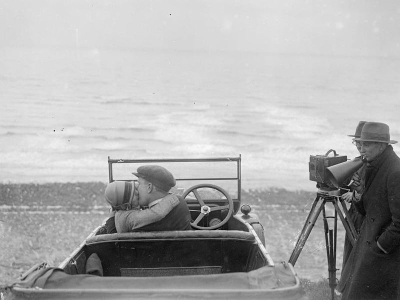 A couple in an open car locked in a passionate embrace for a scene in the film, The Thrill, being shot on Brighton beach.