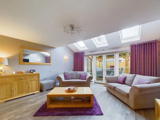The impressive living area boasts three skylights, and a wall of windows to the rear that flood this bright space with natural light