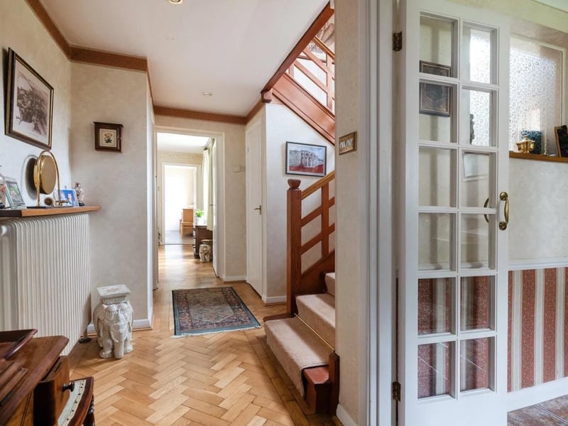 Kitfield Cottage is entered through a covered porch into a hallway with a turned wooden staircase