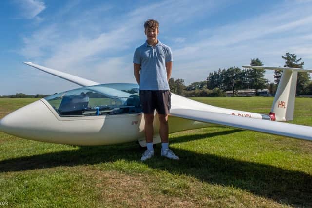 Aidan, proud bursary winner, stands by the club's LS4 Glider which he regularly flies