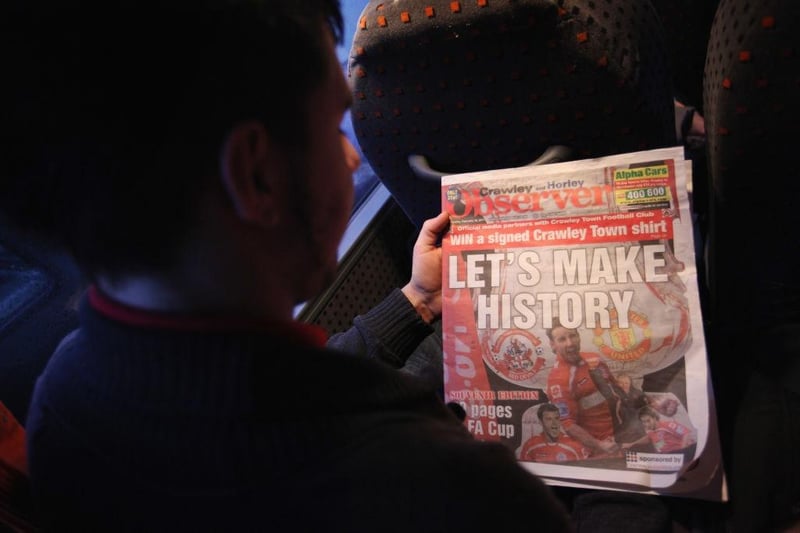 A fan reads the Crawley Observer on the trip to Manchester.
