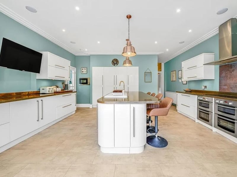 The contemporary kitchen has copper worktops and integrated appliances, a wall-mounted TV point, a breakfast bar and bi-fold doors to the rear garden.