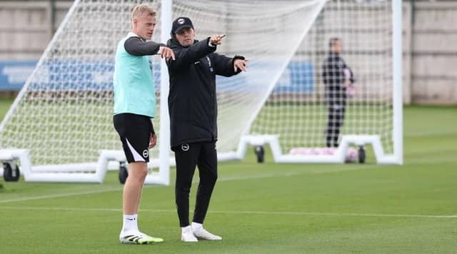 Brighton boss Fabian Hurzeler chats with defender Jan Paul van Hecke as they prepare to face Bournemouth