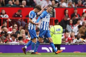 Pascal Gross of Brighton & Hove Albion celebrates with team mate Adam Lallana after scoring their sides second goal at Man United