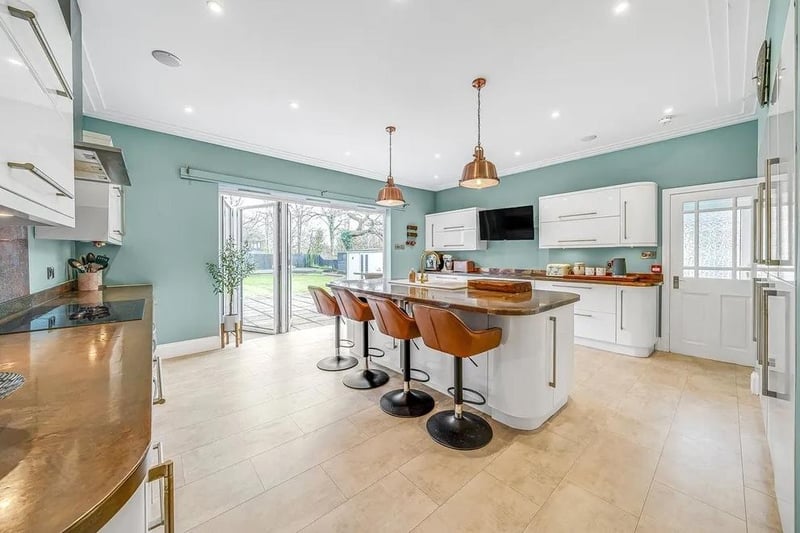 The contemporary kitchen has copper worktops and integrated appliances, a wall-mounted TV point, a breakfast bar and bi-fold doors to the rear garden.