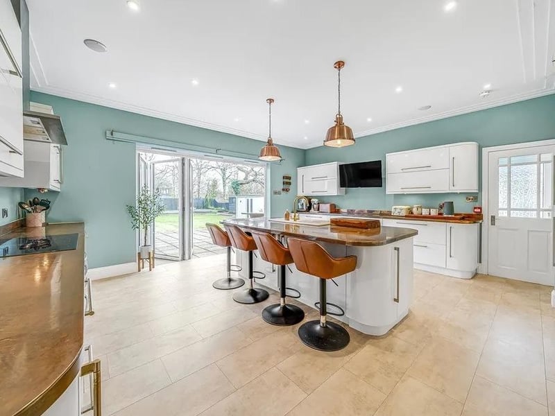 The contemporary kitchen has copper worktops and integrated appliances, a wall-mounted TV point, a breakfast bar and bi-fold doors to the rear garden.
