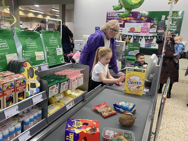 Community champion Alison Whitburn shows Leia how to work the till at Morrisons in Littlehampton