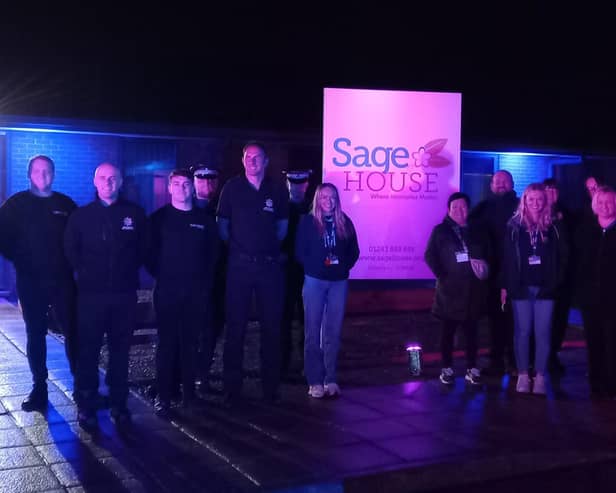 Staff members of Sage House photographed outside the blue and purple lit building.