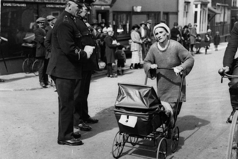 Mrs Edwards, one of the five contestants taking part in the London to Brighton Perambulator Walking Race, passing two policemen at Crawley on 7th April 1923.