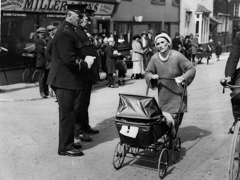 Mrs Edwards, one of the five contestants taking part in the London to Brighton Perambulator Walking Race, passing two policemen at Crawley on 7th April 1923.