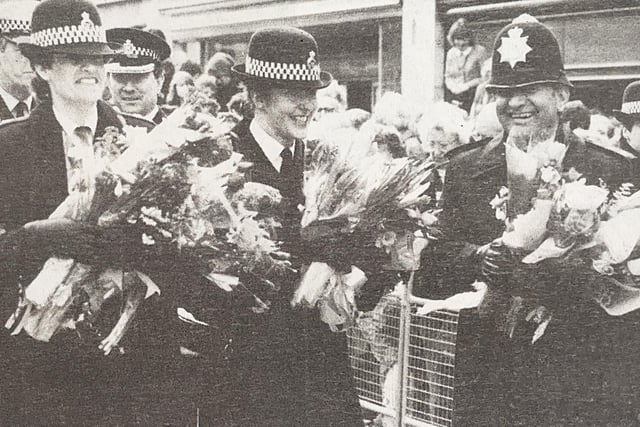 The police gather flowers residents brought to present to the Queen.