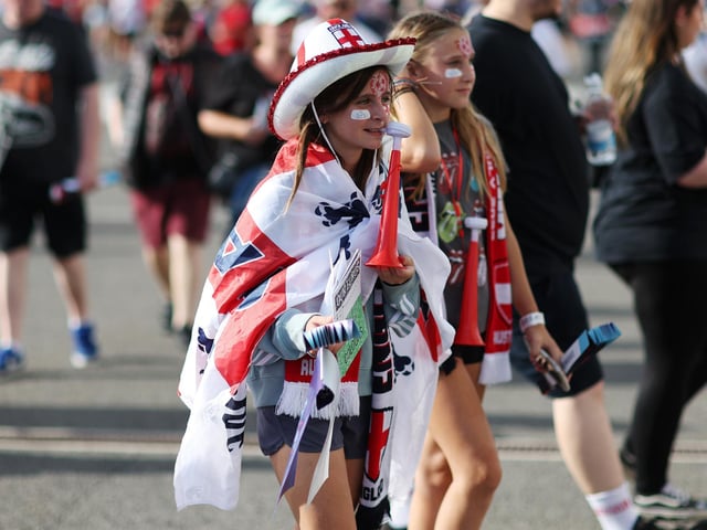 A fan wearing an England flag arrives at the stadium.