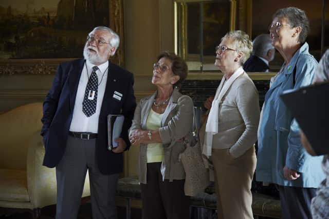 Visitors with a volunteer room steward at Petworth House, West Sussex.