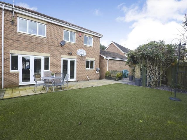 As we step outside, this photo shows the fully enclosed garden at the back. The patio area is ideal for entertaining, while the artificial lawn means low maintenance.