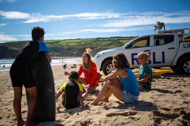 A lifeguard talking to a family on a beach