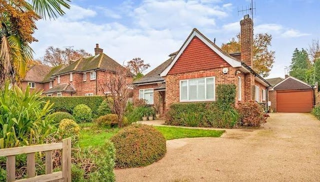 The chalet bungalow has an attractive front garden and driveway with parking for several cars leading to a garage