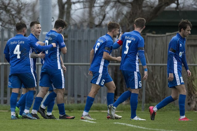 Selsey players celebrate with Shane Brazil (hidden) after he puts the Blues 1-0 up, although the game finished in a 1-1 draw.