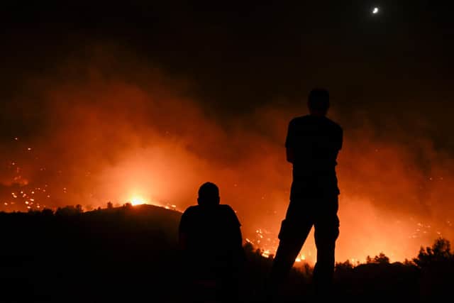 People watch the fires near the village of Malona in the Greek island of Rhodes on July 23, 2023. Tens of thousands of people fled wildfires on Rhodes, as terrified tourists scrambled to get home. Firefighters tackled blazes that erupted in peak tourism season, sparking the country's largest-ever wildfire evacuation -- and leaving flights and holidays cancelled. Picture by SPYROS BAKALIS/AFP via Getty Images