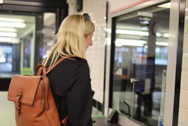 Louise Connop, senior engagement manager, at Sight Loss Councils, stood at a ticket office counter holding her cane. Photo: Sight Loss Councils