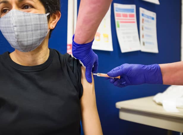 British Asian woman wearing a face mask, getting a Covid 19 vaccine at a vaccination centre in England, UK